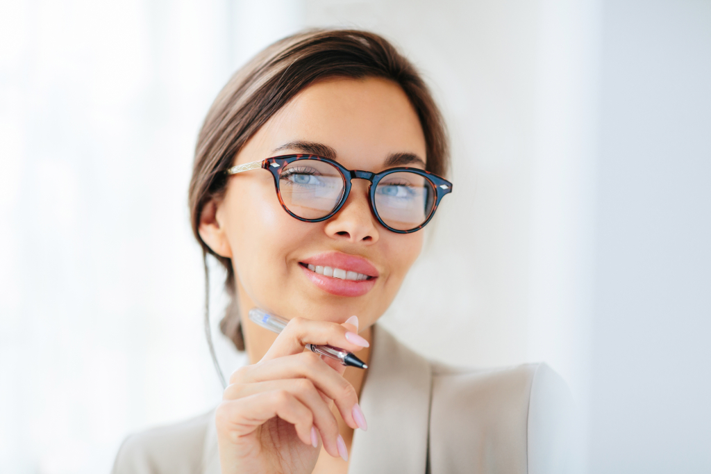 Beautiful executive woman posing with glasses and pen
